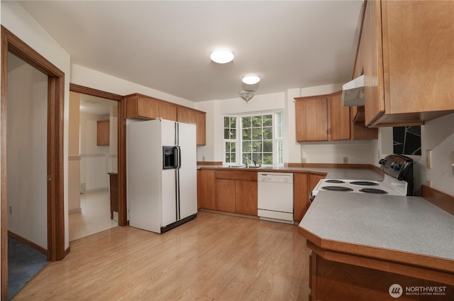 818 295th St E, Roy, WA 98580 - kitchen with white appliances, light wood finished floors, brown cabinetry, a sink, and under cabinet range hood