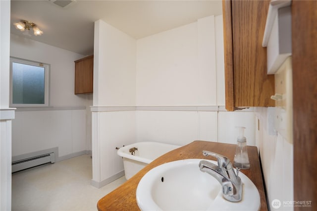 818 295th St E, Roy, WA 98580 - bathroom with baseboard heating, a freestanding bath, a sink, and a wainscoted wall
