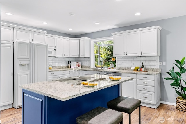 17655 Division Ave NE, Suquamish, WA 98392 - kitchen with paneled built in refrigerator, a kitchen breakfast bar, white cabinets, tasteful backsplash, and recessed lighting