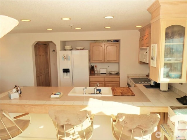 1599 E Ocean Shores Blvd SW Unit 2E, Ocean Shores, WA 98569 - kitchen with white appliances, tile counters, arched walkways, a sink, and a peninsula