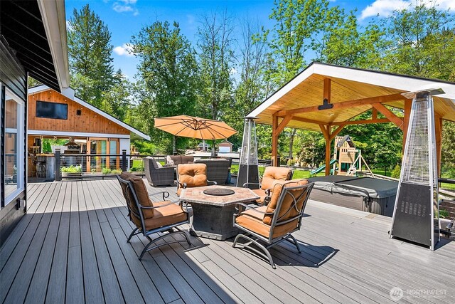 15530 73rd Ave SE, Snohomish, WA 98296 - wooden deck featuring a fire pit, a covered hot tub, a playground, and view of scattered trees
