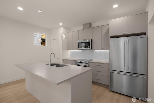 9223A 14th Ave NW, Seattle, WA 98117 - kitchen with stainless steel appliances, a sink, light wood-style flooring, gray cabinetry, and a center island with sink