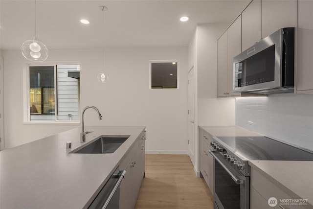 9223A 14th Ave NW, Seattle, WA 98117 - kitchen with stainless steel appliances, a sink, light wood-style floors, tasteful backsplash, and recessed lighting