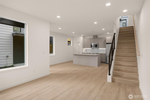 9223A 14th Ave NW, Seattle, WA 98117 - unfurnished living room with light wood finished floors, recessed lighting, stairs, a sink, and baseboards