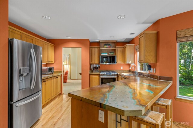 2041 NW Tregaten Ln, Poulsbo, WA 98370 - kitchen featuring appliances with stainless steel finishes, a sink, open shelves, a peninsula, and a kitchen breakfast bar