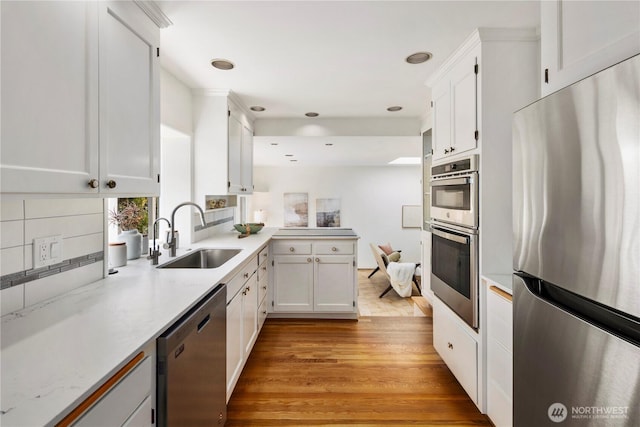 3249 Conkling Pl W, Seattle, WA 98119 - kitchen featuring stainless steel appliances, a sink, a peninsula, white cabinetry, and light wood-style flooring