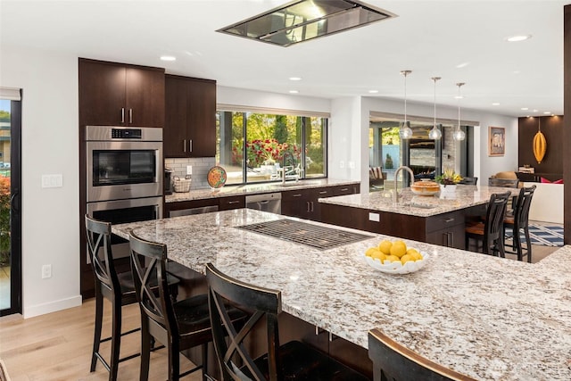 12 Columbia Ky, Bellevue, WA 98006 - kitchen with stainless steel appliances, a sink, a kitchen island with sink, a kitchen breakfast bar, and dark brown cabinetry