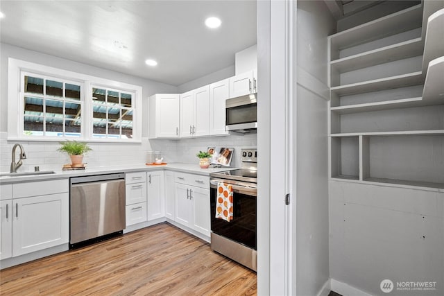 2319 Washington St SE, Olympia, WA 98501 - kitchen with stainless steel appliances, a sink, white cabinetry, backsplash, and light wood-style floors