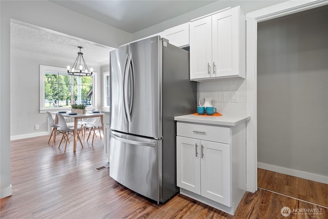 2319 Washington St SE, Olympia, WA 98501 - kitchen with freestanding refrigerator, baseboards, white cabinetry, light countertops, and wood finished floors