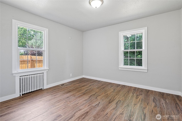 2319 Washington St SE, Olympia, WA 98501 - unfurnished room featuring radiator heating unit, plenty of natural light, wood finished floors, and baseboards