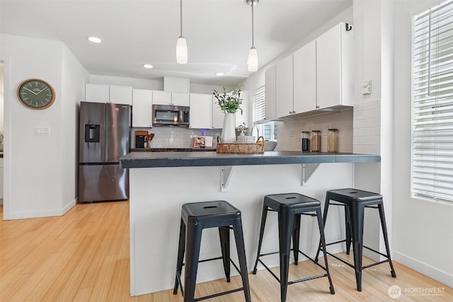 5028 Delridge Way SW Unit C, Seattle, WA 98106 - kitchen with stainless steel appliances, dark countertops, a peninsula, a kitchen bar, and white cabinetry