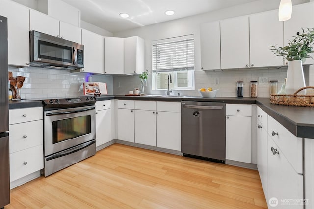 5028 Delridge Way SW Unit C, Seattle, WA 98106 - kitchen with stainless steel appliances, dark countertops, light wood-type flooring, tasteful backsplash, and recessed lighting