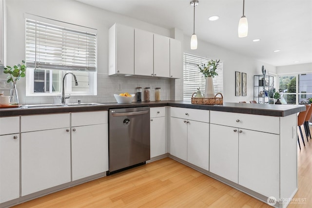 5028 Delridge Way SW Unit C, Seattle, WA 98106 - kitchen with dishwasher, a peninsula, dark countertops, light wood-type flooring, and decorative backsplash