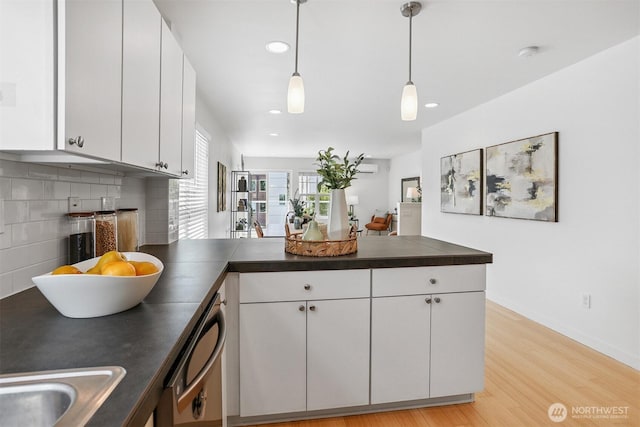 5028 Delridge Way SW Unit C, Seattle, WA 98106 - kitchen with a peninsula, dark countertops, dishwashing machine, white cabinets, and light wood finished floors