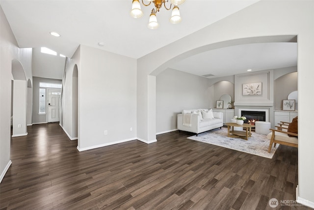 18216 80th Ave E, Puyallup, WA 98375 - living area with arched walkways, a glass covered fireplace, dark wood finished floors, baseboards, and vaulted ceiling