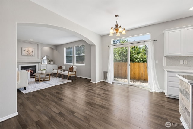 18216 80th Ave E, Puyallup, WA 98375 - living room featuring a glass covered fireplace, arched walkways, a chandelier, dark wood-type flooring, and baseboards