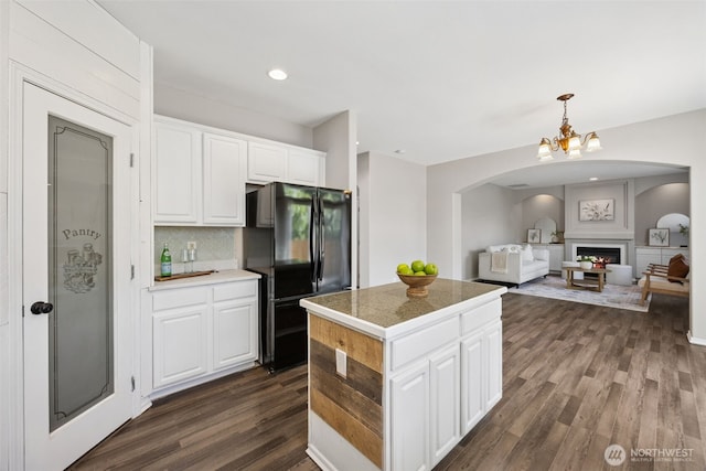18216 80th Ave E, Puyallup, WA 98375 - kitchen featuring arched walkways, freestanding refrigerator, dark wood-style flooring, a kitchen island, and white cabinets
