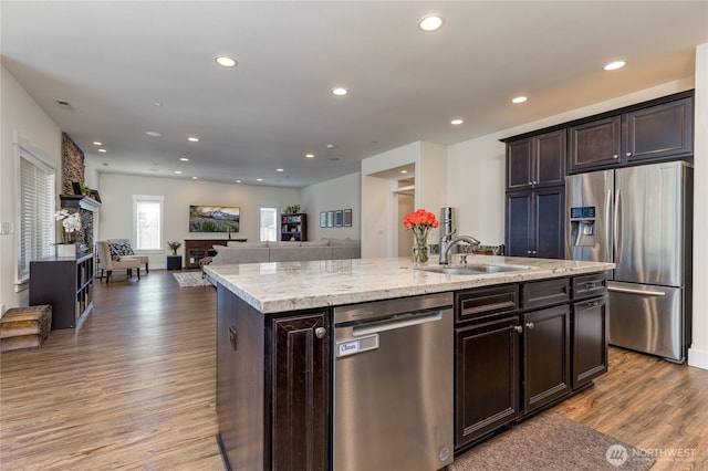 6214 207th Ave E, Bonney Lake, WA 98391 - kitchen with stainless steel appliances, a fireplace, a sink, wood finished floors, and a center island with sink