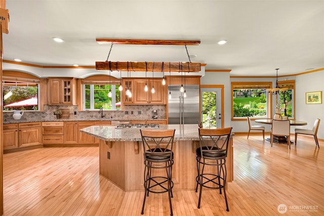 8795 Wood Duck Way, Blaine, WA 98230 - kitchen with appliances with stainless steel finishes, light stone countertops, tasteful backsplash, a center island, and a kitchen bar