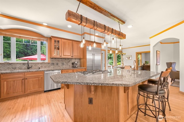 8795 Wood Duck Way, Blaine, WA 98230 - kitchen featuring stainless steel appliances, a breakfast bar area, light wood-type flooring, healthy amount of natural light, and ornamental molding