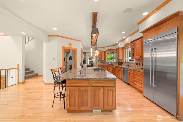 8795 Wood Duck Way, Blaine, WA 98230 - kitchen with stainless steel appliances, light wood finished floors, a kitchen breakfast bar, recessed lighting, and brown cabinets