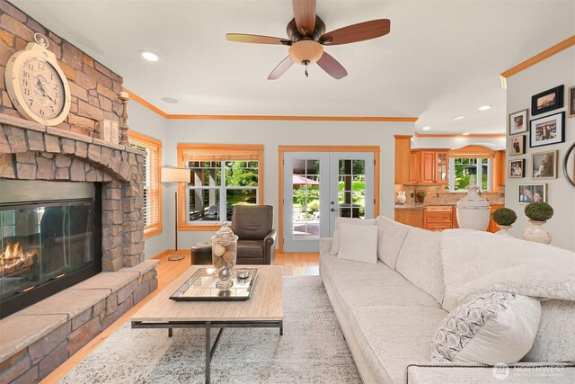 8795 Wood Duck Way, Blaine, WA 98230 - living area with french doors, ornamental molding, light wood finished floors, a stone fireplace, and a ceiling fan