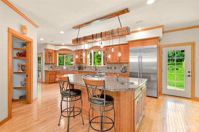 8795 Wood Duck Way, Blaine, WA 98230 - kitchen featuring appliances with stainless steel finishes, ornamental molding, decorative backsplash, a kitchen island with sink, and light wood-type flooring