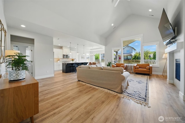 235 Champagne Way, Walla Walla, WA 99362 - living room with light wood finished floors, high vaulted ceiling, a glass covered fireplace, baseboards, and recessed lighting