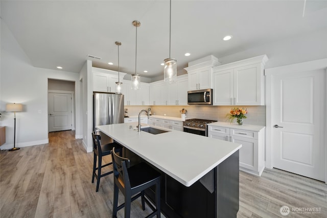 235 Champagne Way, Walla Walla, WA 99362 - kitchen featuring appliances with stainless steel finishes, a sink, a kitchen bar, light wood-style flooring, and decorative backsplash