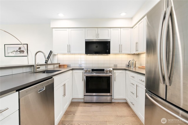215 20th Ave E Unit 203, Seattle, WA 98112 - kitchen featuring appliances with stainless steel finishes, a sink, light wood finished floors, white cabinets, and recessed lighting