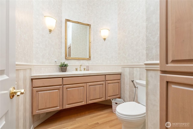 412 N 69th Ave, Yakima, WA 98908 - bathroom featuring wallpapered walls, vanity, toilet, wainscoting, and wood finished floors