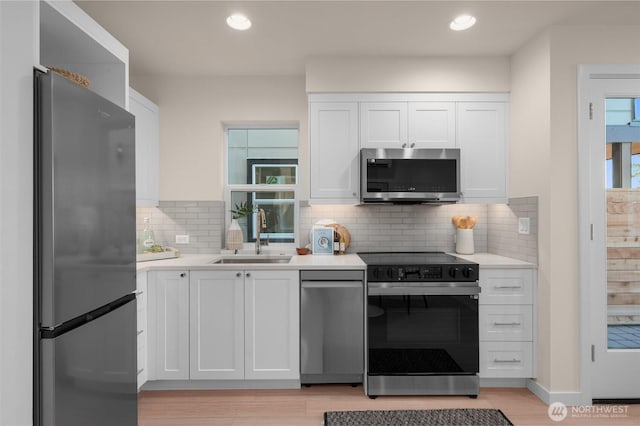 9217B Densmore Ave N, Seattle, WA 98103 - kitchen with stainless steel appliances, a sink, light countertops, white cabinets, and recessed lighting