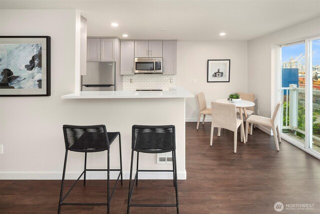 3318 30th Ave SW Unit A502, Seattle, WA 98126 - kitchen featuring stainless steel microwave, refrigerator, a kitchen breakfast bar, light countertops, and dark wood-style floors