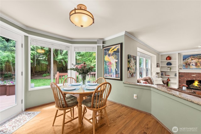 22233 NE 23rd St, Sammamish, WA 98074 - dining room featuring healthy amount of natural light, a brick fireplace, light wood finished floors, and ornamental molding