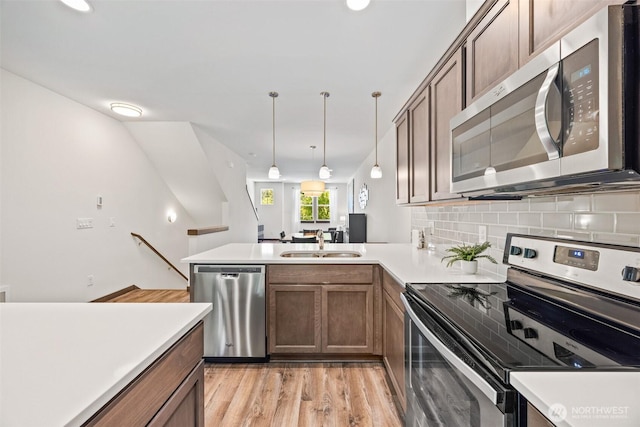 7165 27th Ave SW, Seattle, WA 98106 - kitchen featuring appliances with stainless steel finishes, a sink, light countertops, a peninsula, and backsplash