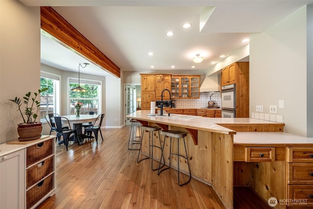 10303 Ski Hill Dr, Leavenworth, WA 98826 - kitchen featuring a kitchen bar, glass insert cabinets, backsplash, light wood finished floors, and recessed lighting