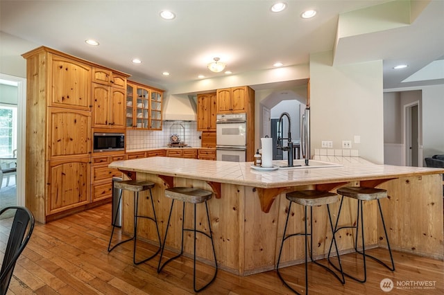 10303 Ski Hill Dr, Leavenworth, WA 98826 - kitchen with stainless steel microwave, double oven, custom exhaust hood, a peninsula, and glass insert cabinets