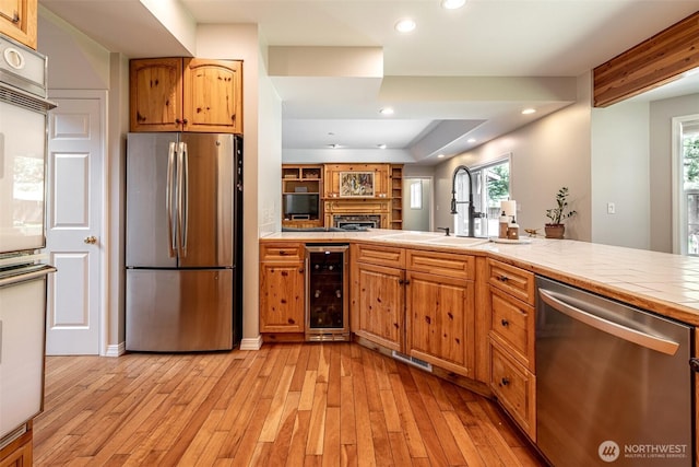 10303 Ski Hill Dr, Leavenworth, WA 98826 - kitchen with stainless steel appliances, beverage cooler, tile counters, light wood-style flooring, and plenty of natural light