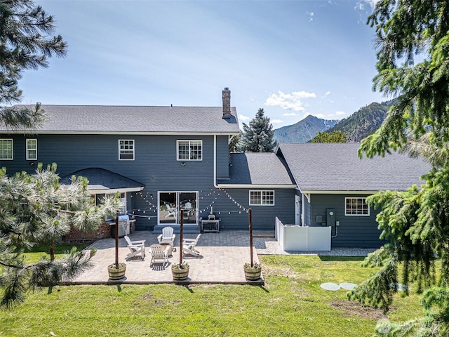10303 Ski Hill Dr, Leavenworth, WA 98826 - back of property with a chimney, a lawn, a mountain view, and a patio