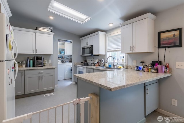 16016 11th Ave E, Tacoma, WA 98445 - kitchen with white appliances, a sink, washing machine and clothes dryer, a peninsula, and a kitchen bar