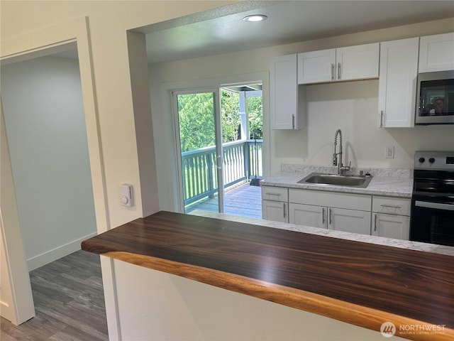 7041 E Washington St, Port Orchard, WA 98366 - kitchen with stainless steel appliances, a sink, butcher block countertops, wood finished floors, and white cabinetry