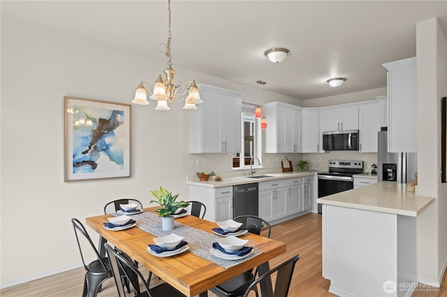 12611 13th Ave SE, Everett, WA 98208 - kitchen with stainless steel appliances, a sink, a chandelier, light countertops, and light wood finished floors