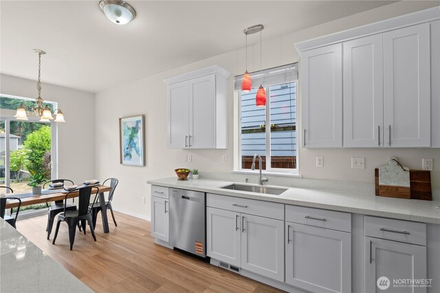12611 13th Ave SE, Everett, WA 98208 - kitchen with stainless steel dishwasher, a sink, a chandelier, white cabinetry, and hanging light fixtures