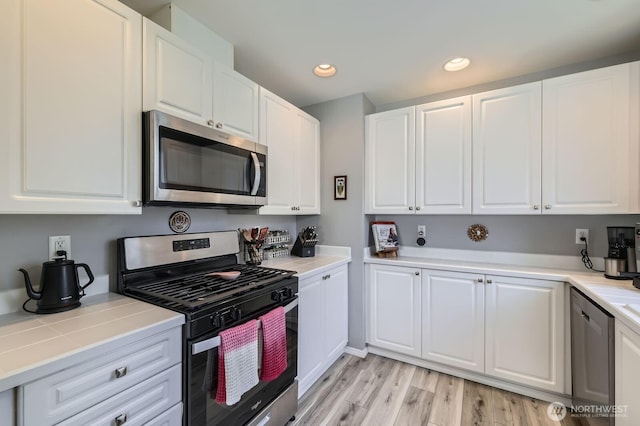 800 96th Ave NE Unit G201, Lake Stevens, WA 98258 - kitchen with appliances with stainless steel finishes, white cabinetry, recessed lighting, light wood-style floors, and tile counters