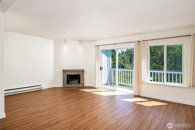 8823 Holly Dr Unit H207, Everett, WA 98208 - unfurnished living room featuring baseboard heating, wood finished floors, a textured ceiling, a brick fireplace, and baseboards
