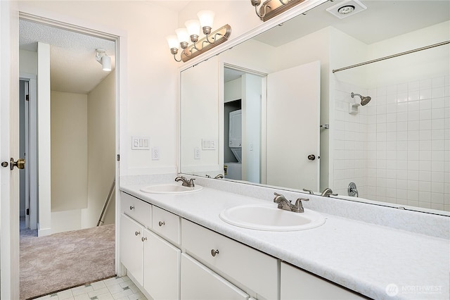 8823 Holly Dr Unit H207, Everett, WA 98208 - bathroom featuring stacked washing machine and dryer, double vanity, and a textured ceiling