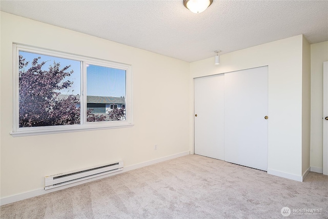 8823 Holly Dr Unit H207, Everett, WA 98208 - unfurnished bedroom featuring baseboard heating, a closet, carpet, baseboards, and a textured ceiling