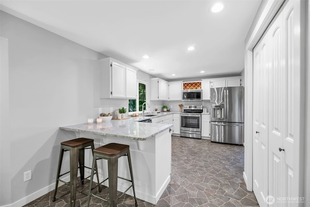 10704 25th Pl NE, Lake Stevens, WA 98258 - kitchen with appliances with stainless steel finishes, a peninsula, recessed lighting, dark stone finish flooring, and white cabinetry