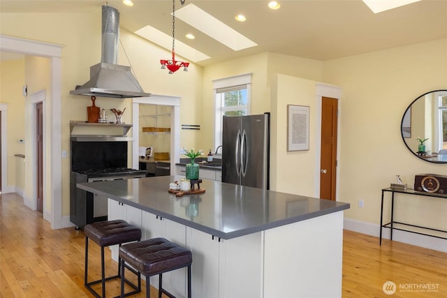 11744 NE Sand Point Way, Seattle, WA 98125 - kitchen with freestanding refrigerator, a skylight, wall chimney range hood, dark countertops, and light wood-style floors