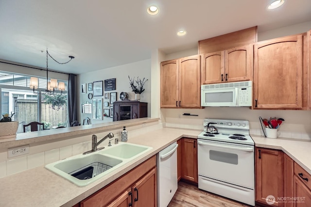 10829 19th Ave SE Unit 3C, Everett, WA 98208 - kitchen with white appliances, a sink, light countertops, a chandelier, and light wood-style floors